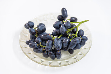 Bunch of seedless black grape on a plate,seasonal fruit isolated on white background