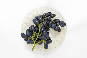 Bunch of seedless black grape on a plate,seasonal fruit isolated on white background