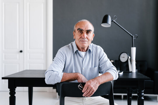 Positive mature businessman sitting at table in workplace
