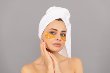 sensual lady with terry towel use facial golden eye patch for skin, spa