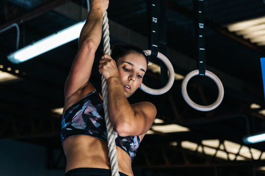 Strong sportswoman exercising on rope in gym