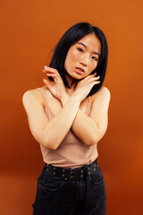 Obraz premium young pretty asian woman cheerful smiling posing on warm brown background, lifestyle people concept
