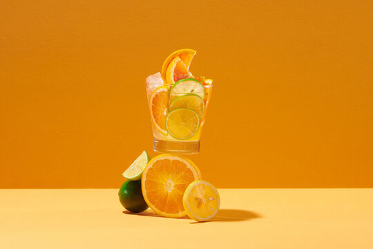 Glassware with refreshing citrus fruits cocktail on color background - Powered by Adobe