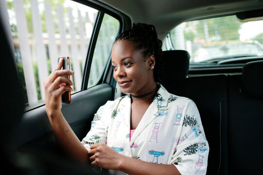 Young attractive woman inside a car looking at her smart phone.