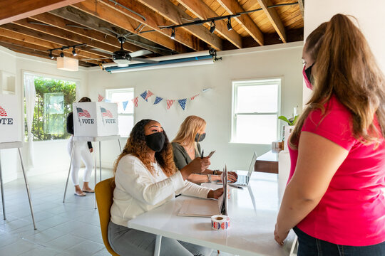 Female Poll Workers Checking a Voter's Identification.