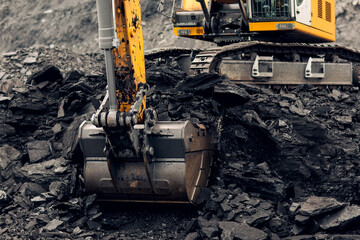 Excavator loads coal into the back of a heavy mining dump truck. Open pit coal mining. © Igor Makarov