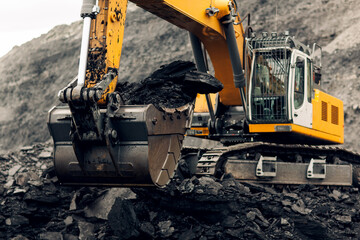 Excavator loads coal into the back of a heavy mining dump truck. Open pit coal mining. © Igor Makarov