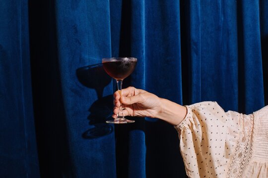 hand with cocktail against blue textile background