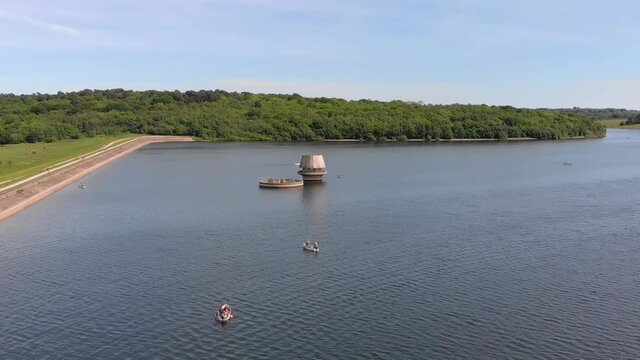 Aerial flyover showing boats von Bewl lake visiting draw off towers with forest in background. Bewl Water, Kent