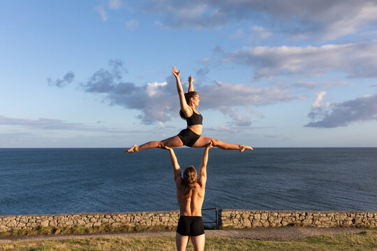 Young woman in splits on young man's arms