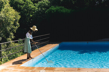 Black Woman cleaning pool in summer day