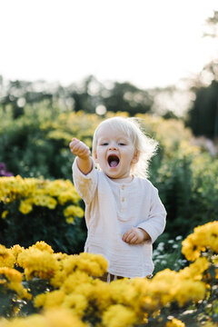 A little girl stands among the flowers in the garden
