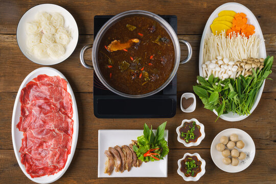 set menu of Thai style beef hot pot with thick chinese soup on wooden table