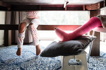 Child with broken leg sits at table with sibling