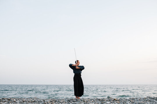 Samurai practicing against sea and evening sky