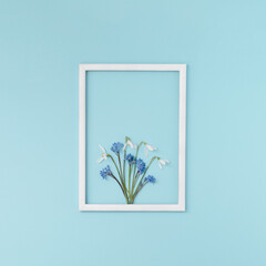 Creative layout made with spring flowers on blue background with frame. Spring minimal concept.