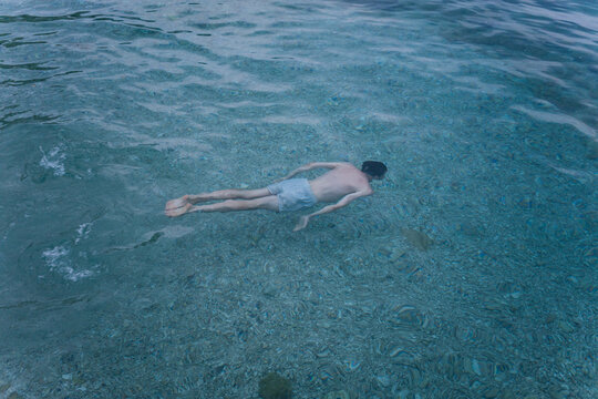Anonymous young adult man swiming in the sea