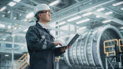 Portrait of a Professional Heavy Industry Asian Engineer/Worker Wearing Safety Uniform and Hard Hat Uses Laptop Computer