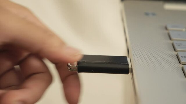 Person inserting plug in flashdisk into usb port in laptop personal computer, data transfer device concept