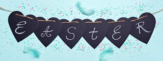 Happy easter banner. Garland with Easter word, feathers and sugar sprinkles on blue background. Flat lay