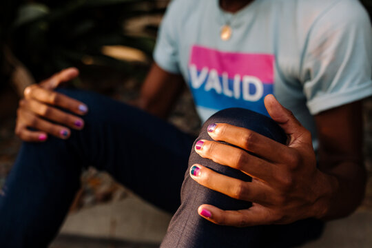 Torso of black male wearing VALID t-shirt sitting on ground grasping knees