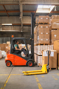 The worker transports freight using a forklift
