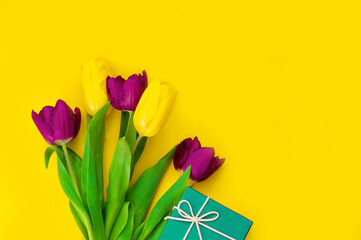 Bouquet of beautiful yellow and purple tulips and gift boxes on a yellow background. Concept for International Women's Day, Mother's Day, birthday background. Top view. copy space