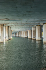 Underside view of a concrete bridge over water.