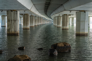 Underside view of a concrete bridge over water.
