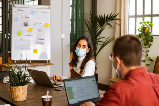 Focused female and man freelancer working at office wearing protective face mask due to the coronavirus
