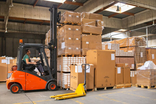 The worker transports freight using a forklift