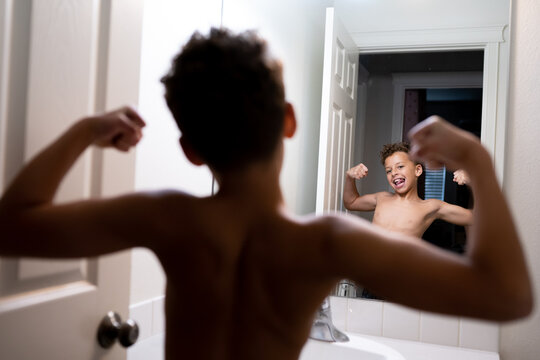 Young boy flexing in a mirror