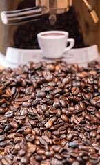 grãos de café sobre à mesa com máquina de café expresso atrás 