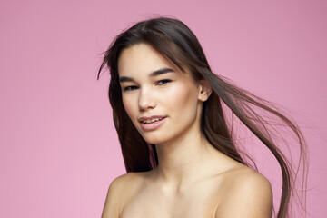 Pretty brunette naked shoulders clear skin pink background