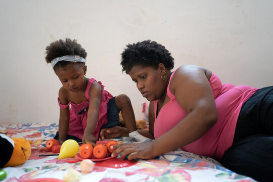 Black Mother And Little Daughter Playing On The Bed.