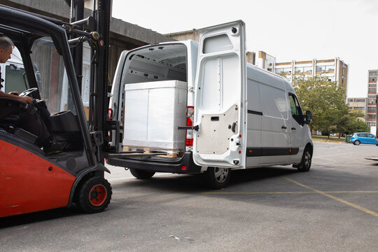 The worker transports freight into a van using a forklift