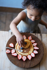 イチゴとブルーベリーで飾られたライオンのパンケーキを食べる女の子