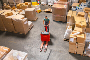 One man operates the pallet jack in a warehouse full of shipping goods