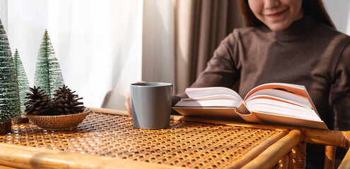 Obraz na płótnie Canvas Closeup image of a beautiful young asian woman reading book at home