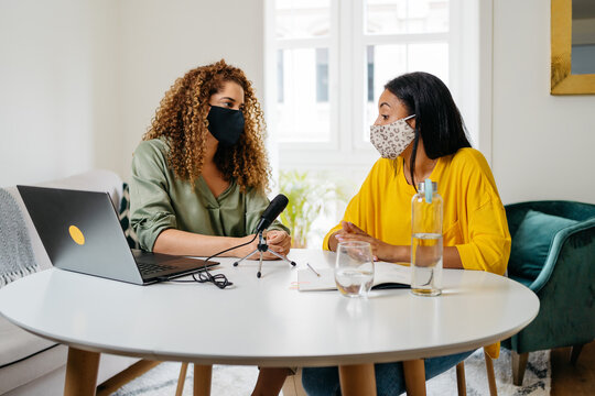 Ethnic women wearing masks recording podcast together - Powered by Adobe