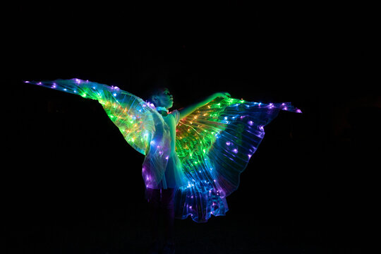 Night photo of girl in light-up LED wing costume