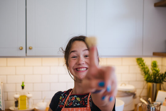 Young girl baking by herself in the kitchen and taste testing th