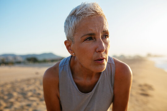 Tired sportswoman resting during training on beach
