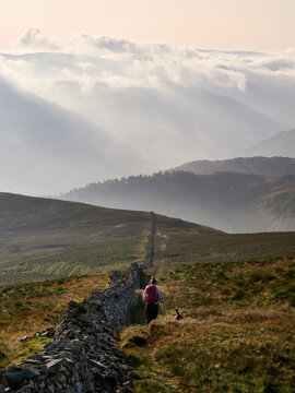 Female walker descending from Hart Side to Ullswater on a misty morning. Lake District, UK.