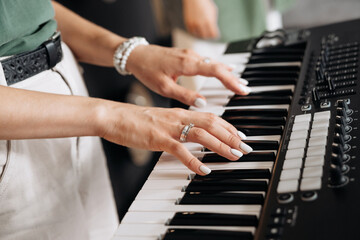 Crop musician playing electric piano in studio