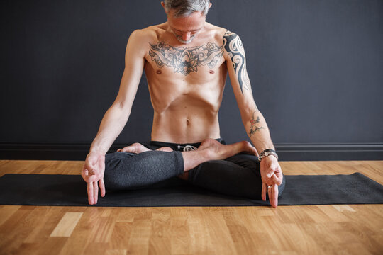 Skinny tattooed man breathing during meditation