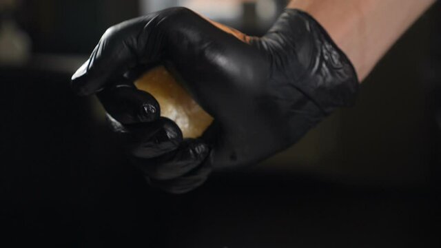 Hand squeeze fresh lemon. Lemon juice drains from pulp and drips. male hand in black glove squeezing fresh lemon half, making juice, close up. Slow motion. juice dribbling out. Cooking in kitchen. hd