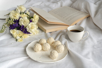 Morning. Coffee,chocolate,book and flowers on the bed 