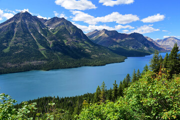 Naklejka na ściany i meble an incredible view in summer from the goat haunt hike overlook in goat haunt, glacier national park, montana, over the mountains, forests, and water of waterton lakes national park in alberta, canada