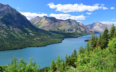 Fototapeta na wymiar an incredible view in summer from the goat haunt hike overlook in goat haunt, glacier national park, montana, over the mountains, forests, and water of waterton lakes national park in alberta, canada